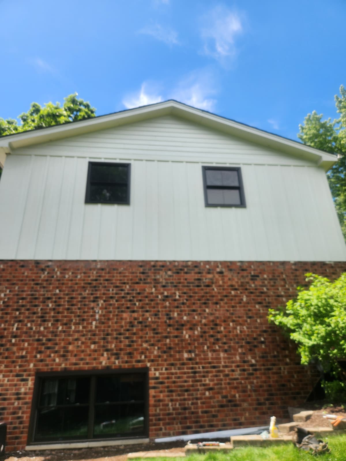 Gable end of Oak Lawn home with new sage vertical siding over red brick